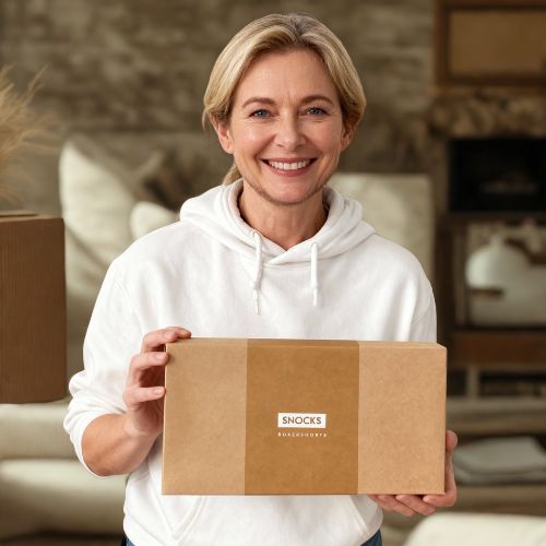 Person holding a brown box labelled 'Snocks' indoors.